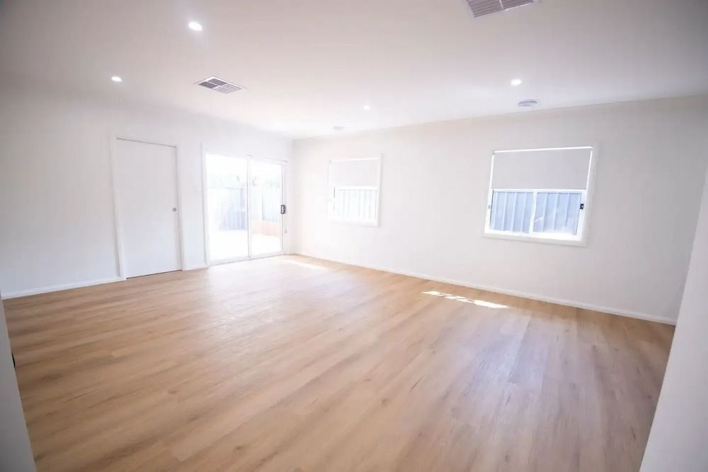 Empty, Bright Room With Hardwood Floors, White Walls, and Large Sliding Glass Door — Nielsen Construction in Wagga Wagga, NSW