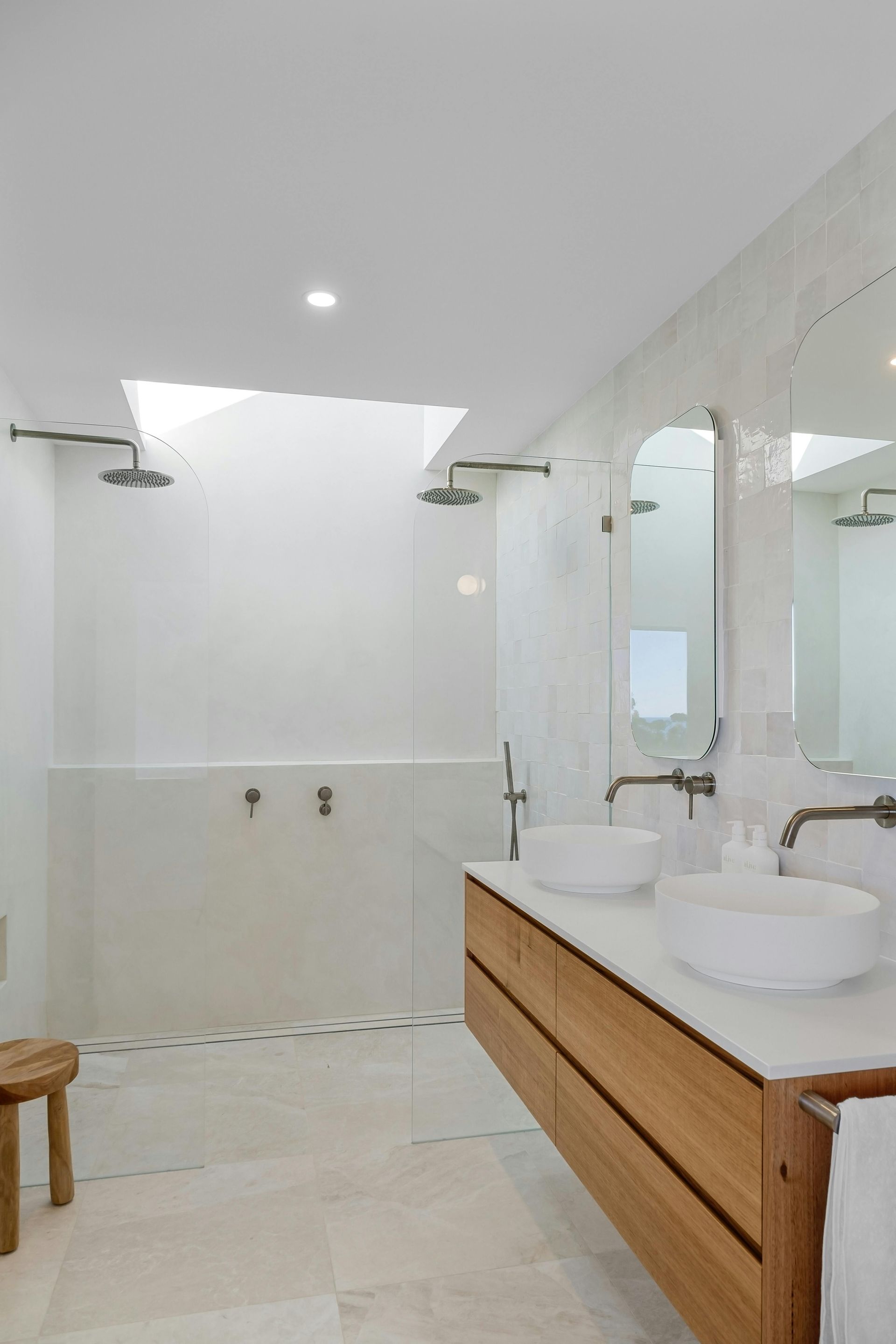 Bright white bathroom with a skylight, dual vanities, and a walk-in shower — Nielsen Construction in Wagga Wagga, NSW