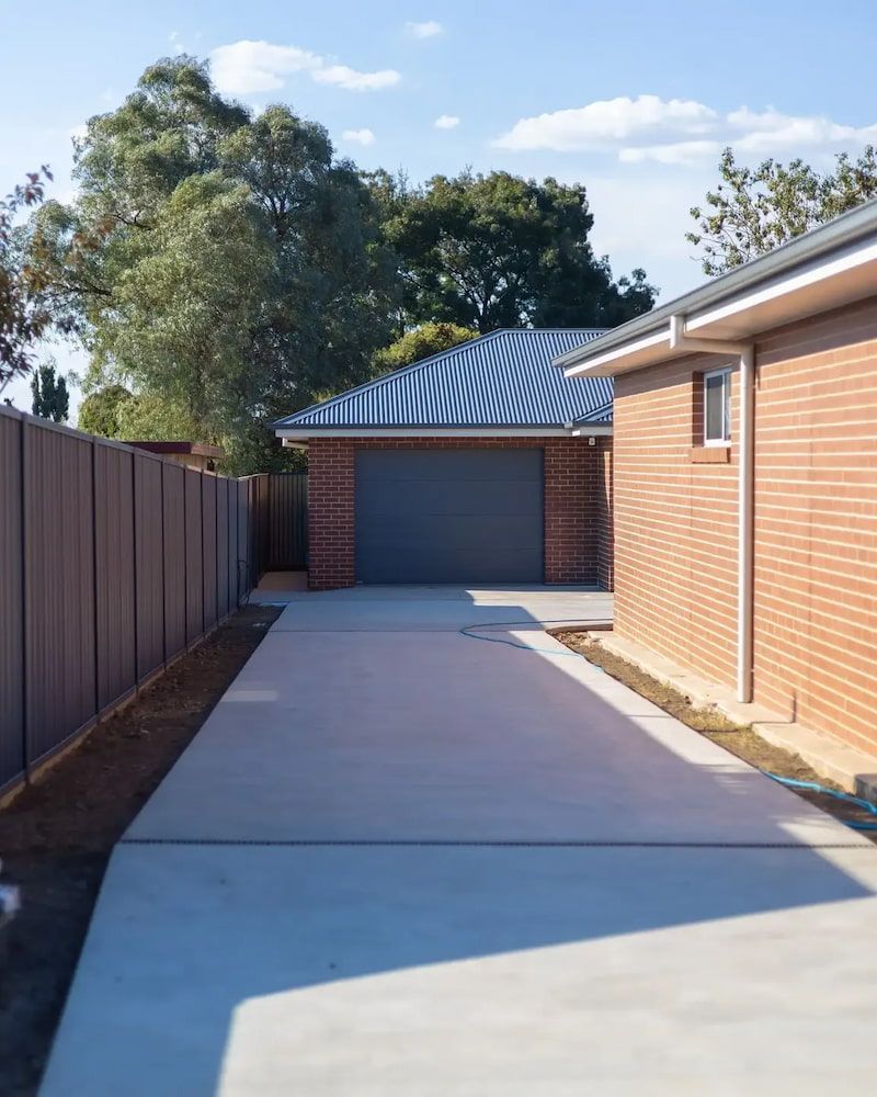 Concrete Driveway Leading to a Brick Garage With a Grey Door — Nielsen Construction in Wagga Wagga, NSW