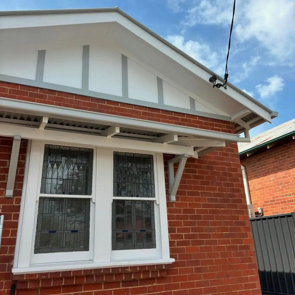 Red Brick House With White and Grey Trim, Window With Stained Glass, Blue Sky — Nielsen Construction in Wagga Wagga, NSW