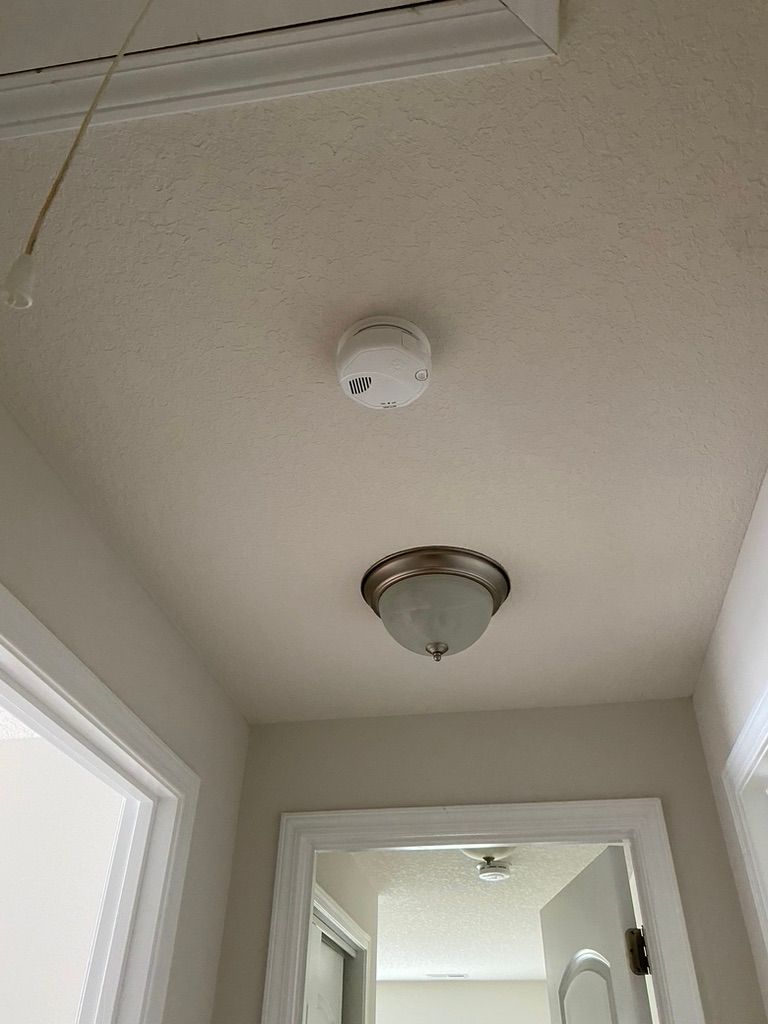 A ceiling with a smoke detector and a light fixture. A doorway and window are visible.