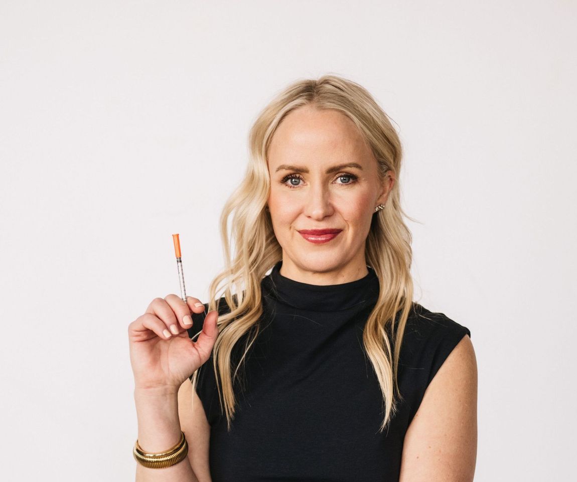 A woman is sitting in a chair holding a glass of wine.