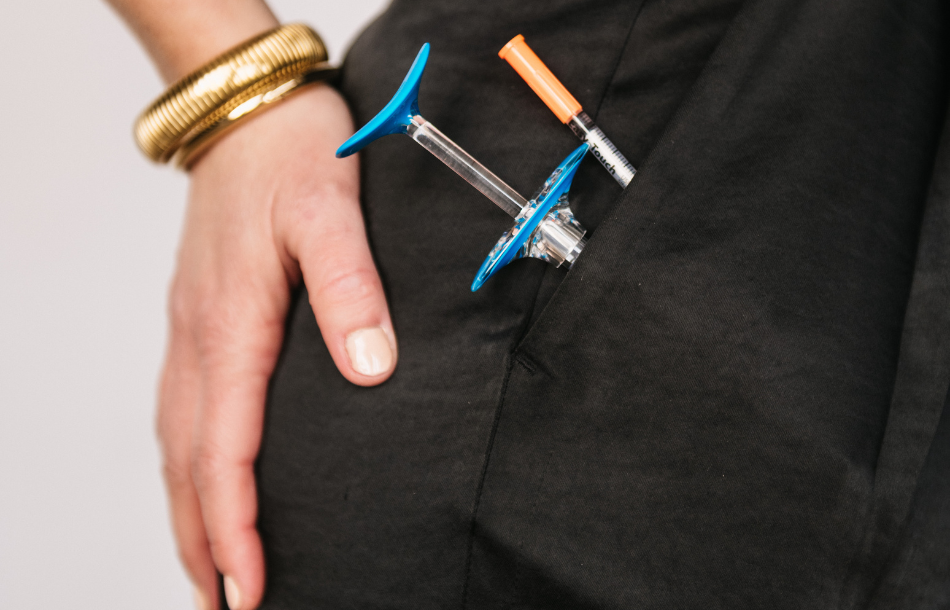 A woman is holding two syringes in her pocket.