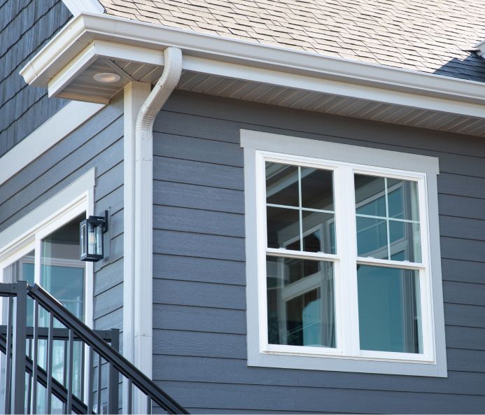 A gray house with a white window and stairs