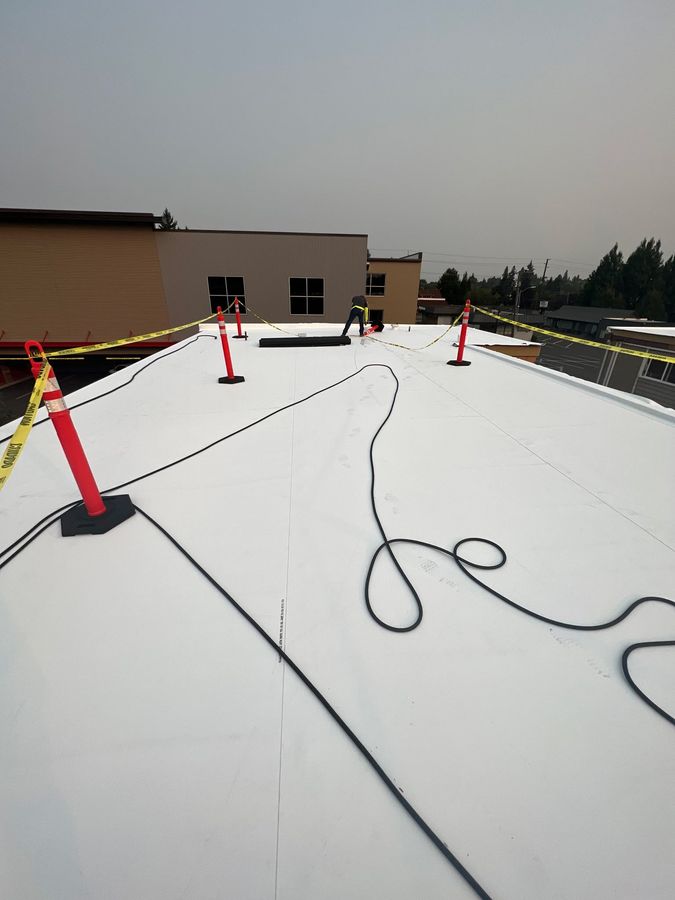 Picture of a Portland Commercial Roofing Pro worker cleaning up the job site after finishing a roof replacement project