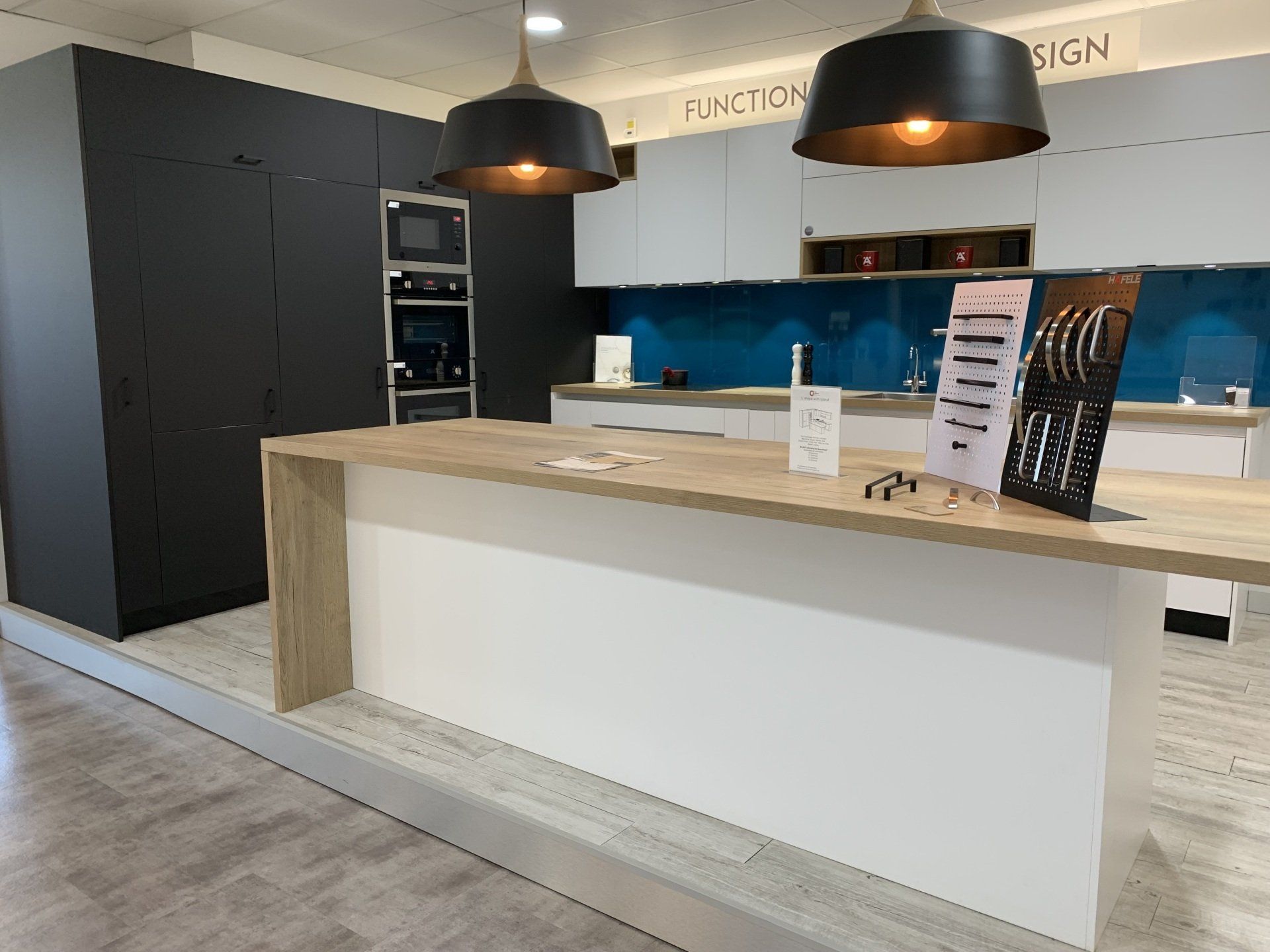 Modern kitchen display with white and gray cabinets, island, and appliances.