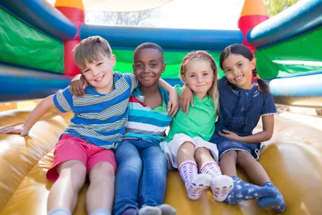 Eine Gruppe Kinder sitzt auf einem Hüpfburg.