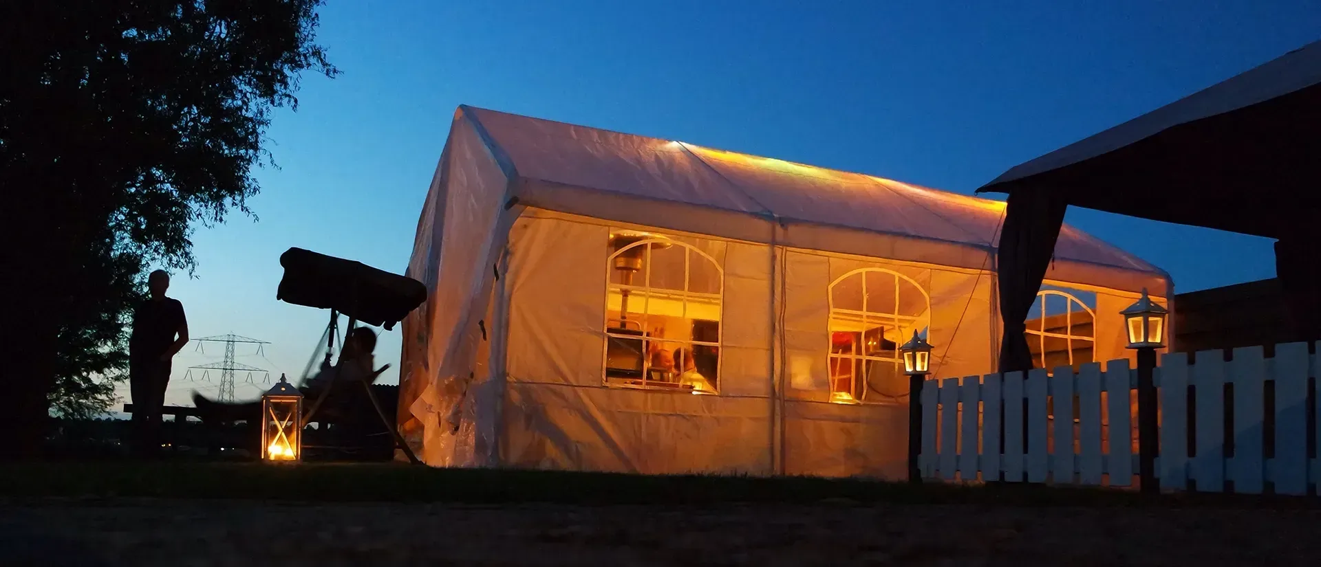 Ein großes weißes Zelt ist nachts beleuchtet.