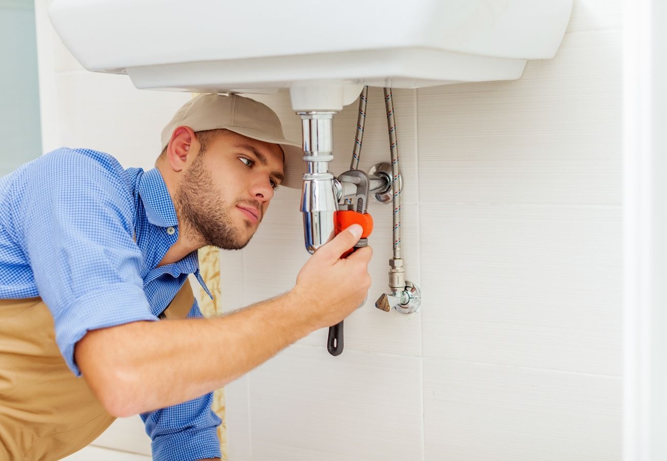 A plumber is fixing a sink in a bathroom.