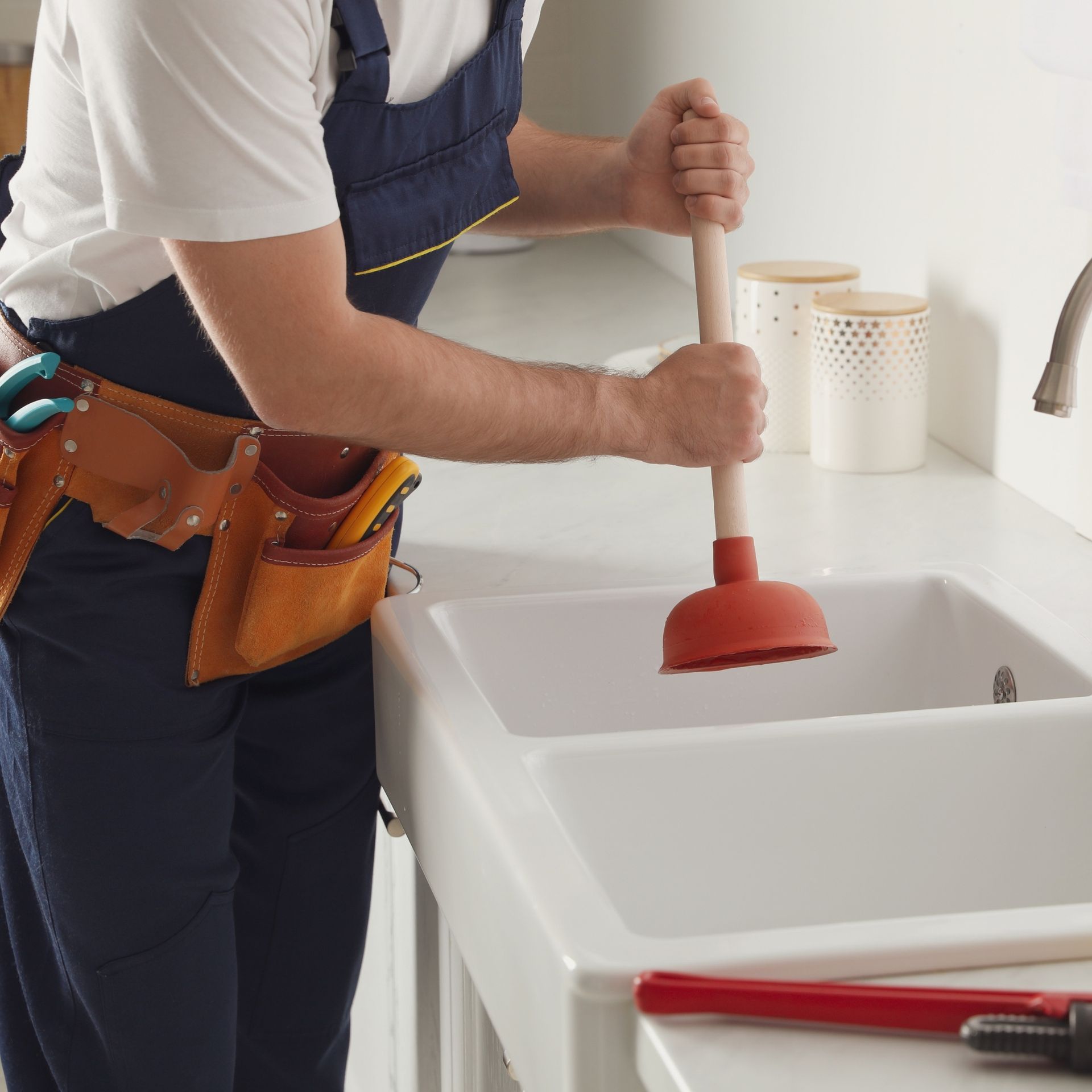 A man is using a plunger to fix a sink