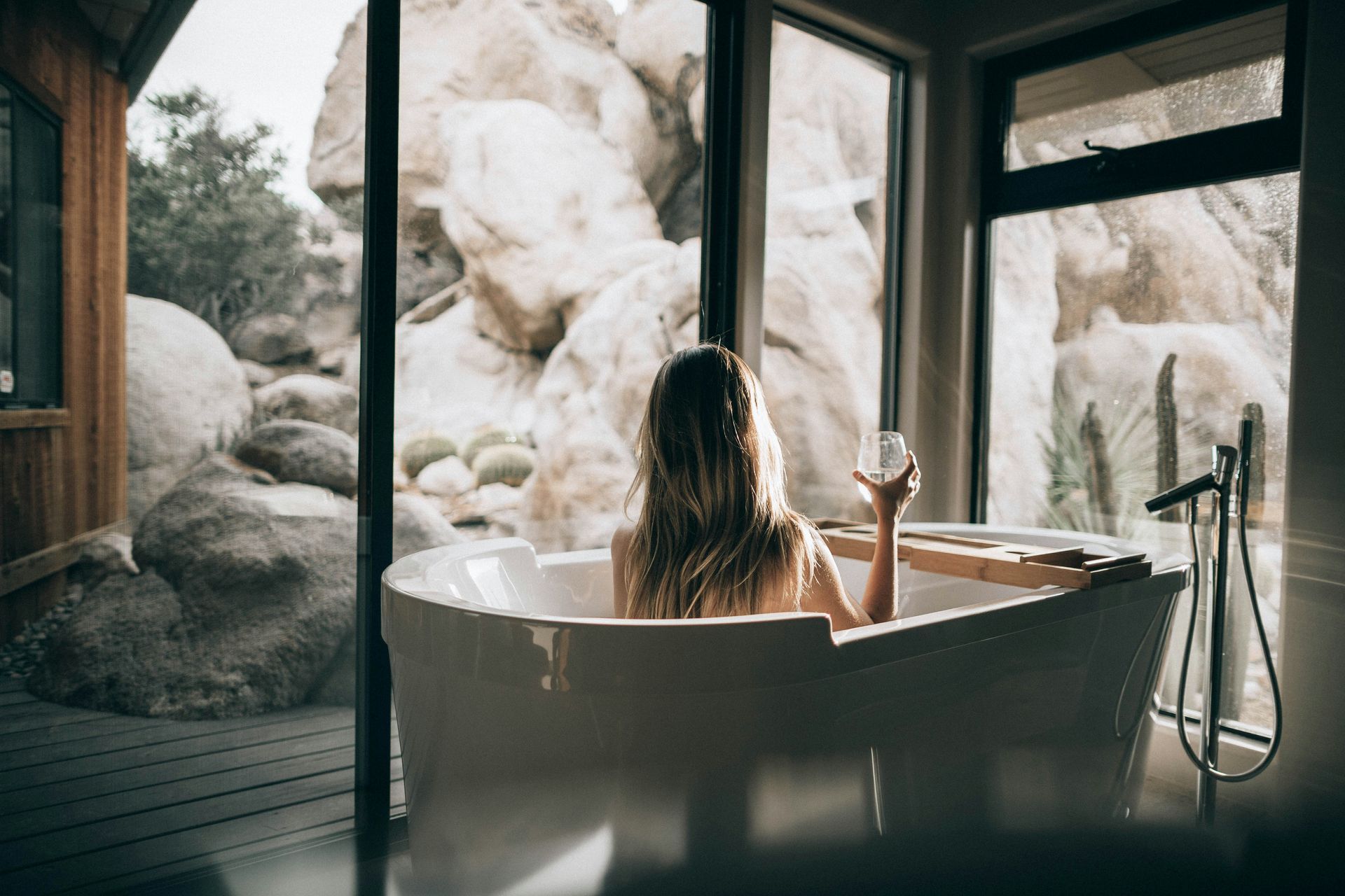 A woman is sitting in a bathtub holding a glass of wine.