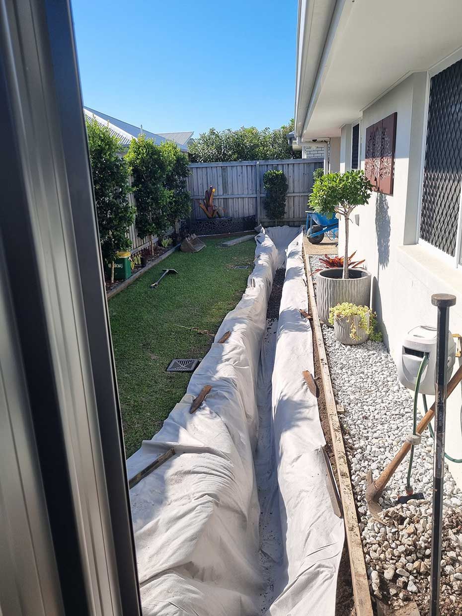 A Drainage System is Being Installed in the Backyard of a House — All Aspects Landscaping In Peregian Beach, QLD