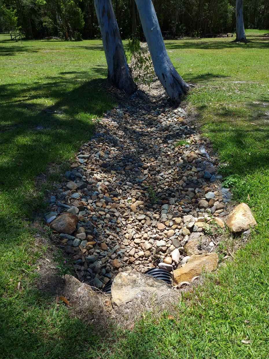 A Stream of Water is Running Through a Grassy Field — All Aspects Landscaping In Peregian Beach, QLD