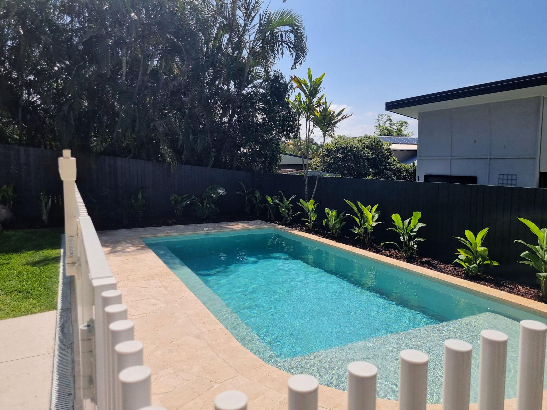 White house with a veranda, stairs, and a landscaped front yard on a sunny day. — All Aspects Landscaping In Peregian Beach, QLD