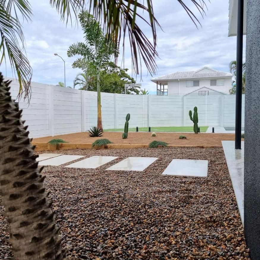 A Backyard With A White Fence And A Palm Tree — All Aspects Landscaping In Maroochy River, QLD