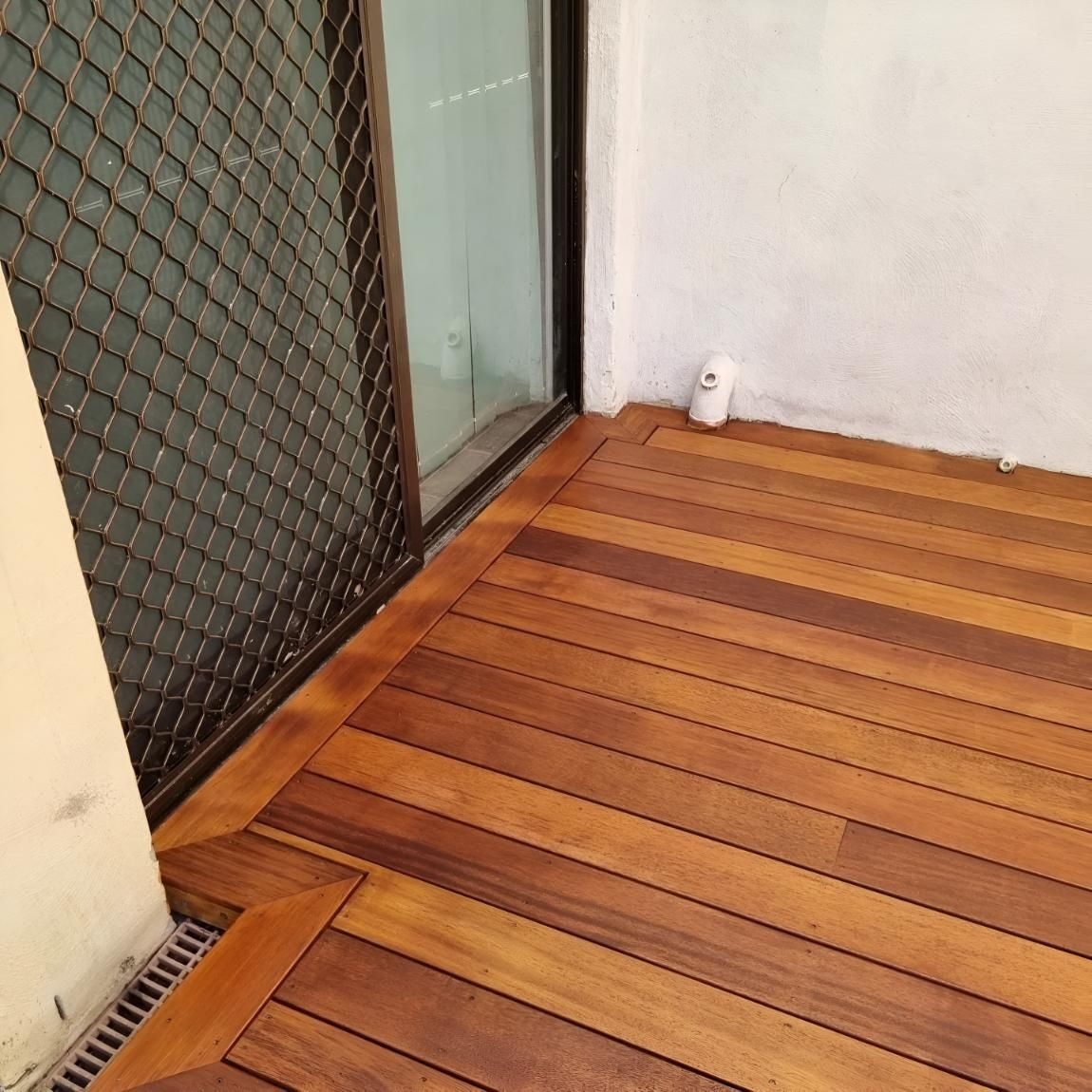 A Wooden Deck With A Sliding Glass Door In The Background — All Aspects Landscaping In Peregian Beach, QLD