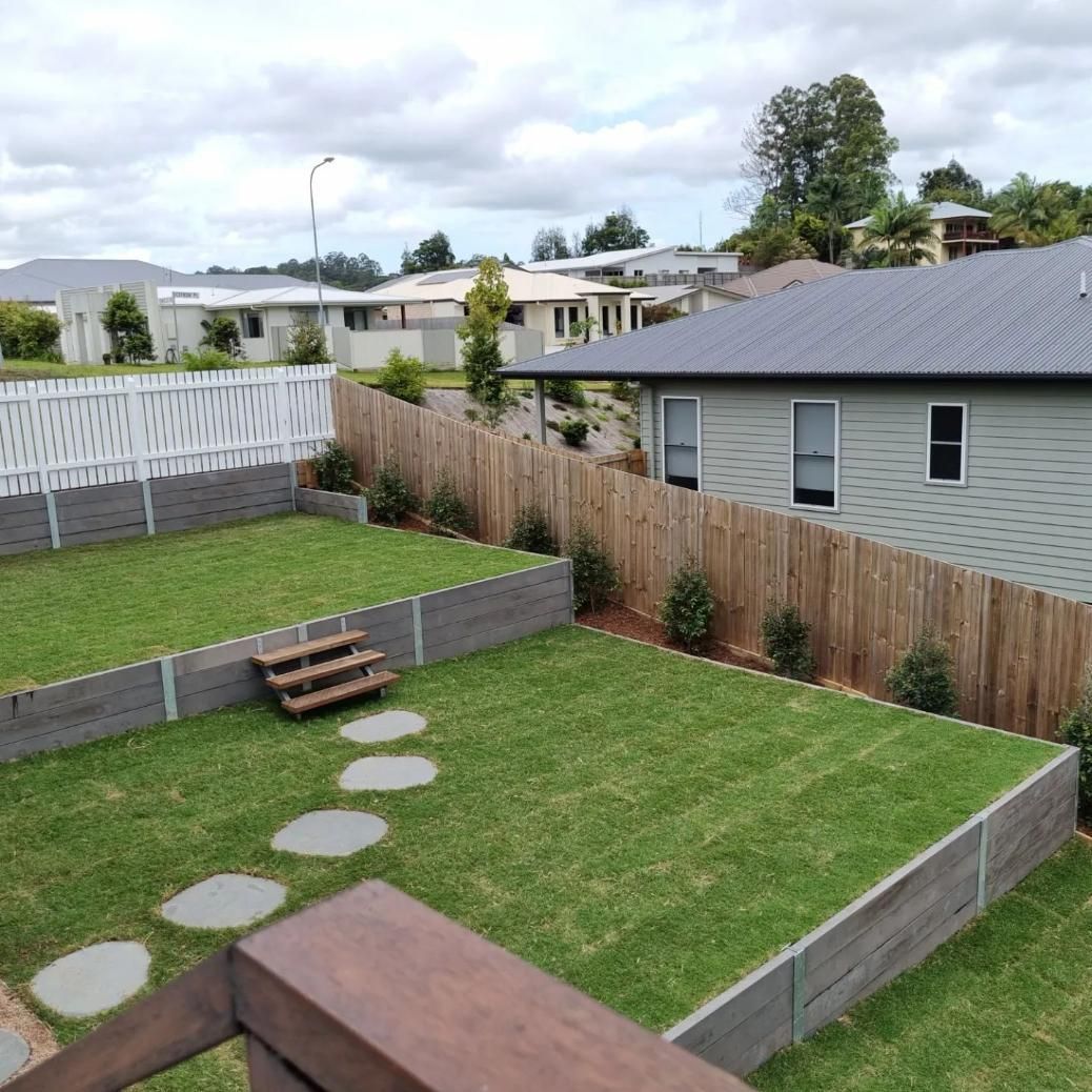 A Backyard With A Wooden Fence And A House In The Background — All Aspects Landscaping In Maroochydore, QLD
