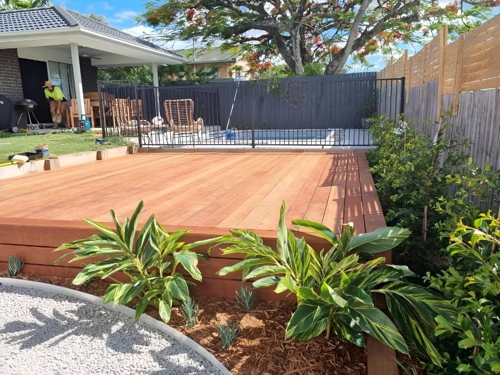 A Wooden Deck With A Pool In The Background And A House In The Background — All Aspects Landscaping In Peregian Beach, QLD