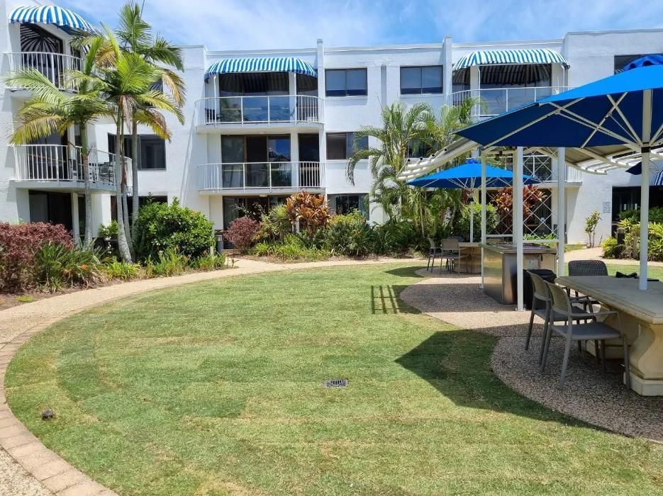 A Large Lawn With Umbrellas And Tables In Front Of A Building — All Aspects Landscaping In Peregian Springs, QLD