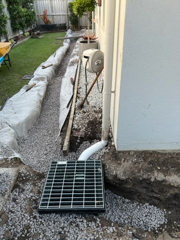 A Drain is Being Installed on the Side of a House — All Aspects Landscaping In Peregian Beach, QLD