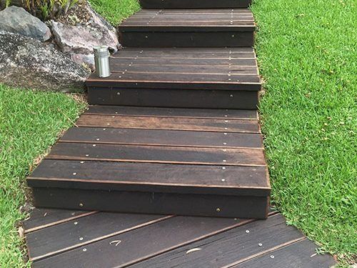 A Wooden Walkway With Stairs Leading Up To A Grassy Area — All Aspects Landscaping In Peregian Beach, QLD