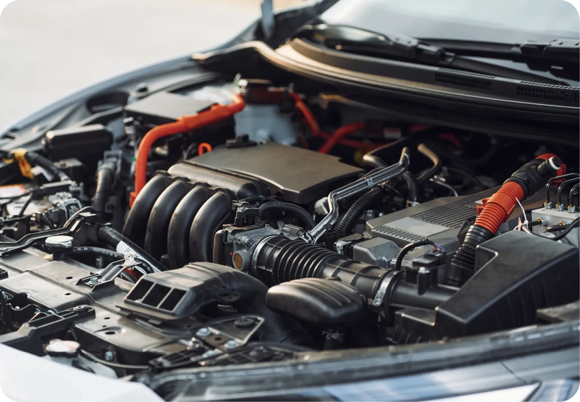 Engine bay of a modern hybrid vehicle with prominent bright orange high-voltage cables and black engine components.