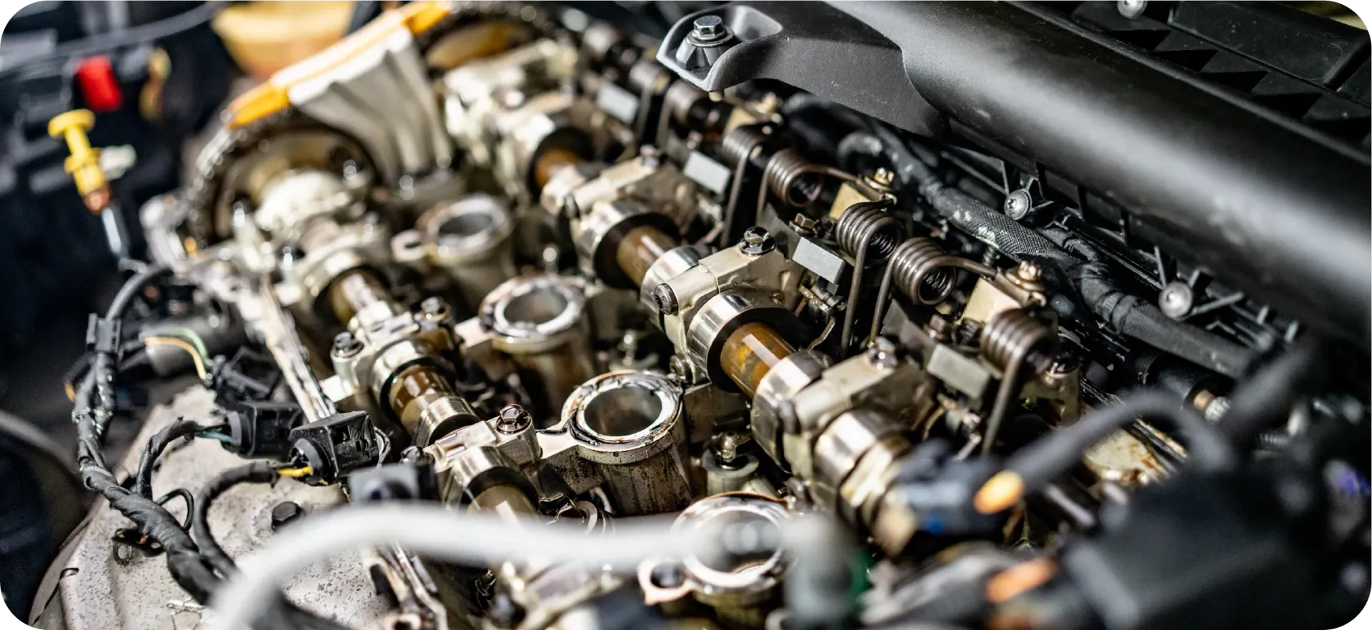 A close-up view of an open internal combustion engine showing exposed camshafts, valves, and mechanical components.