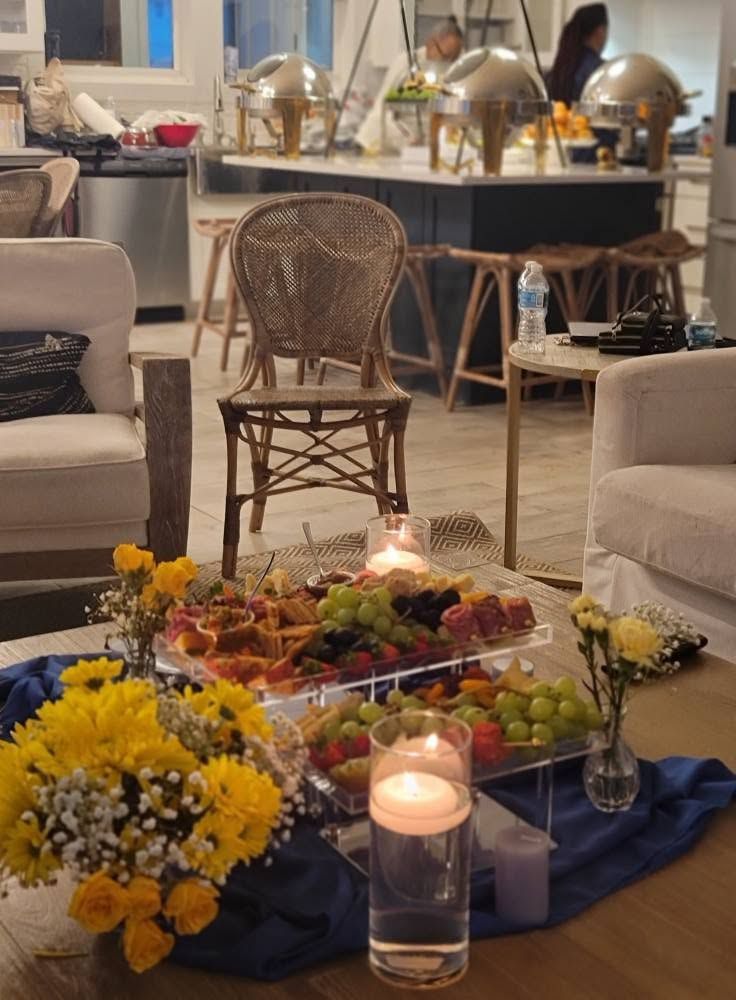 Elegant buffet table with flowers, candles, and fruit in a cozy lounge area