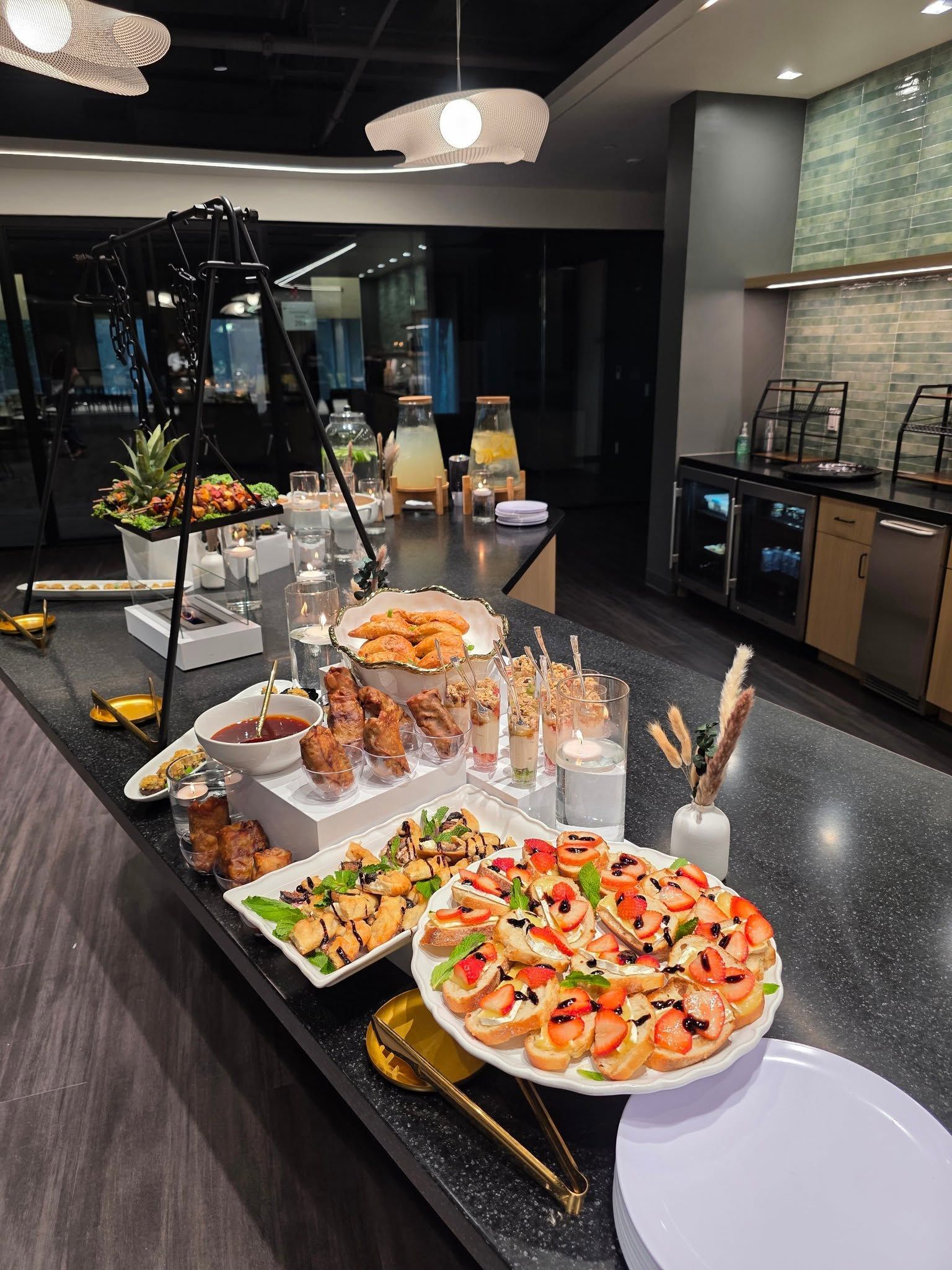 Outdoor buffet table with colorful fruit platters, pastries, and appetizers arranged on trays