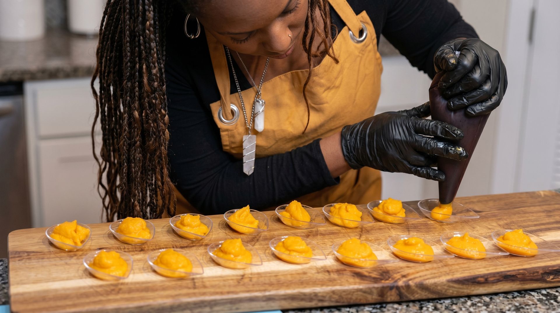 Person serving desserts at a buffet counter in a warmly lit restaurant