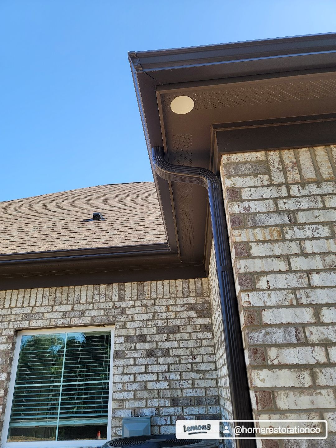 Brown gutters and soffit on a brick house under a blue sky.