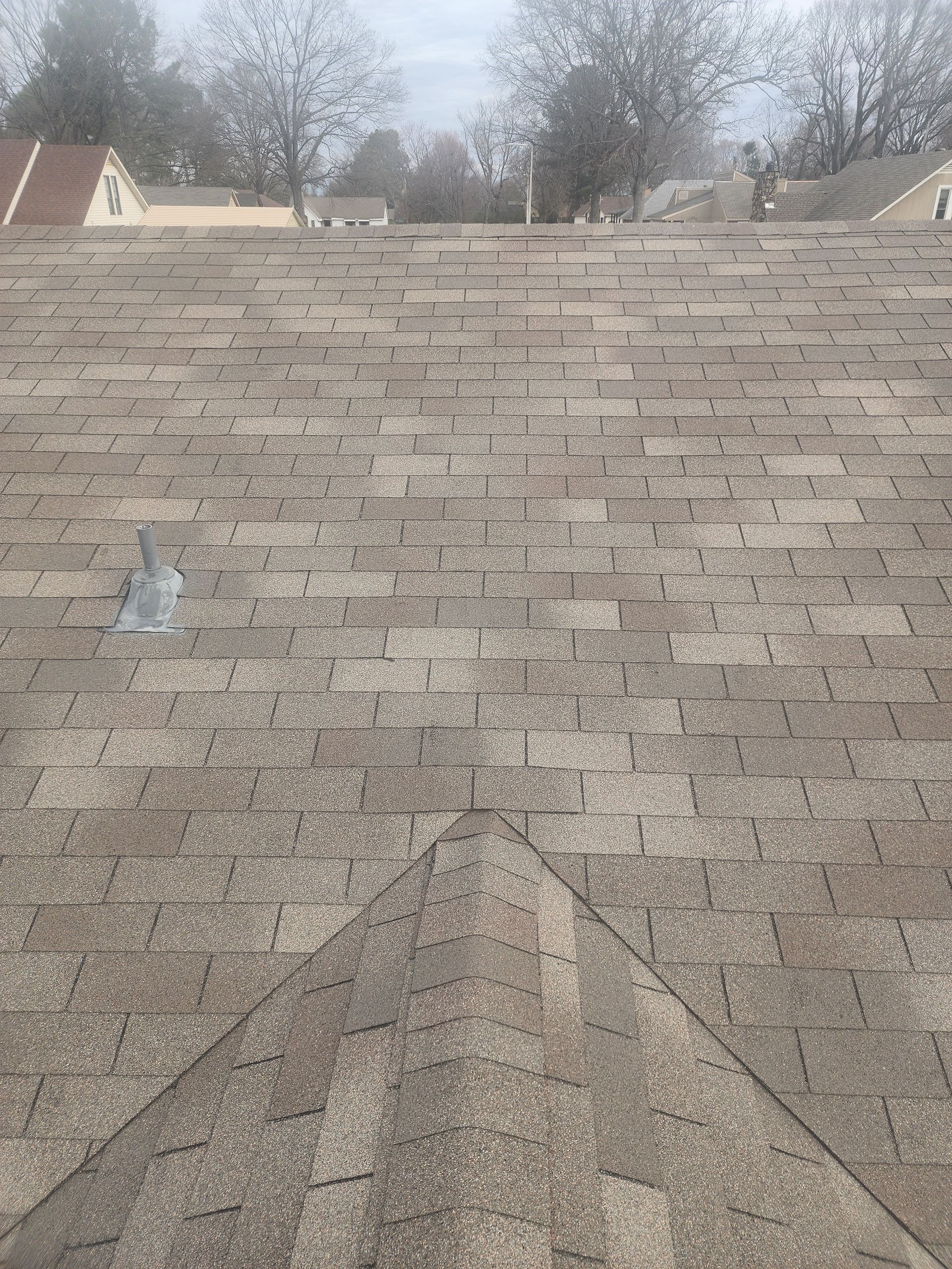 Overhead view of a brown asphalt shingle roof with some metal attachments.
