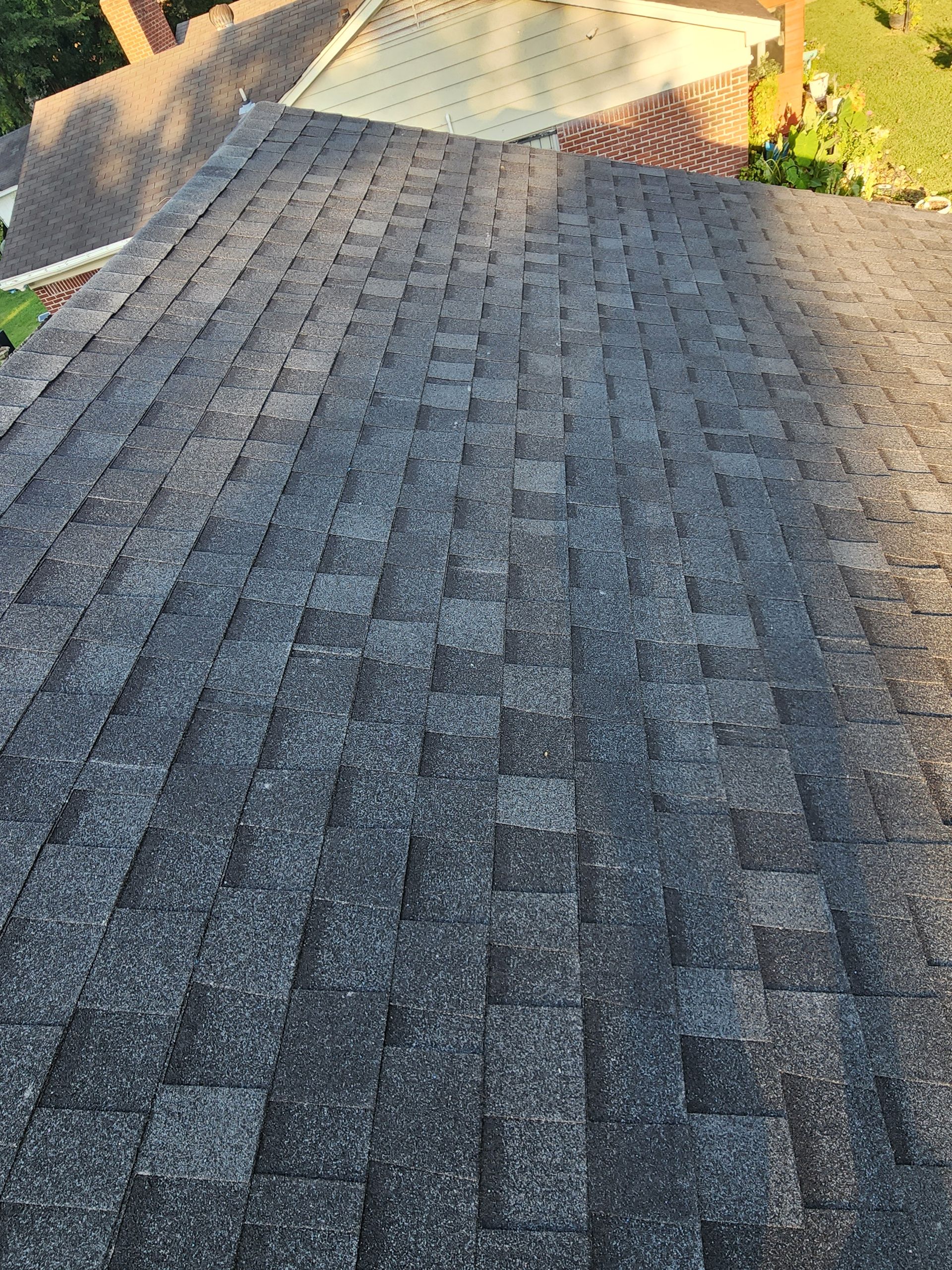 Dark gray asphalt shingle roof with visible granules, viewed from above.