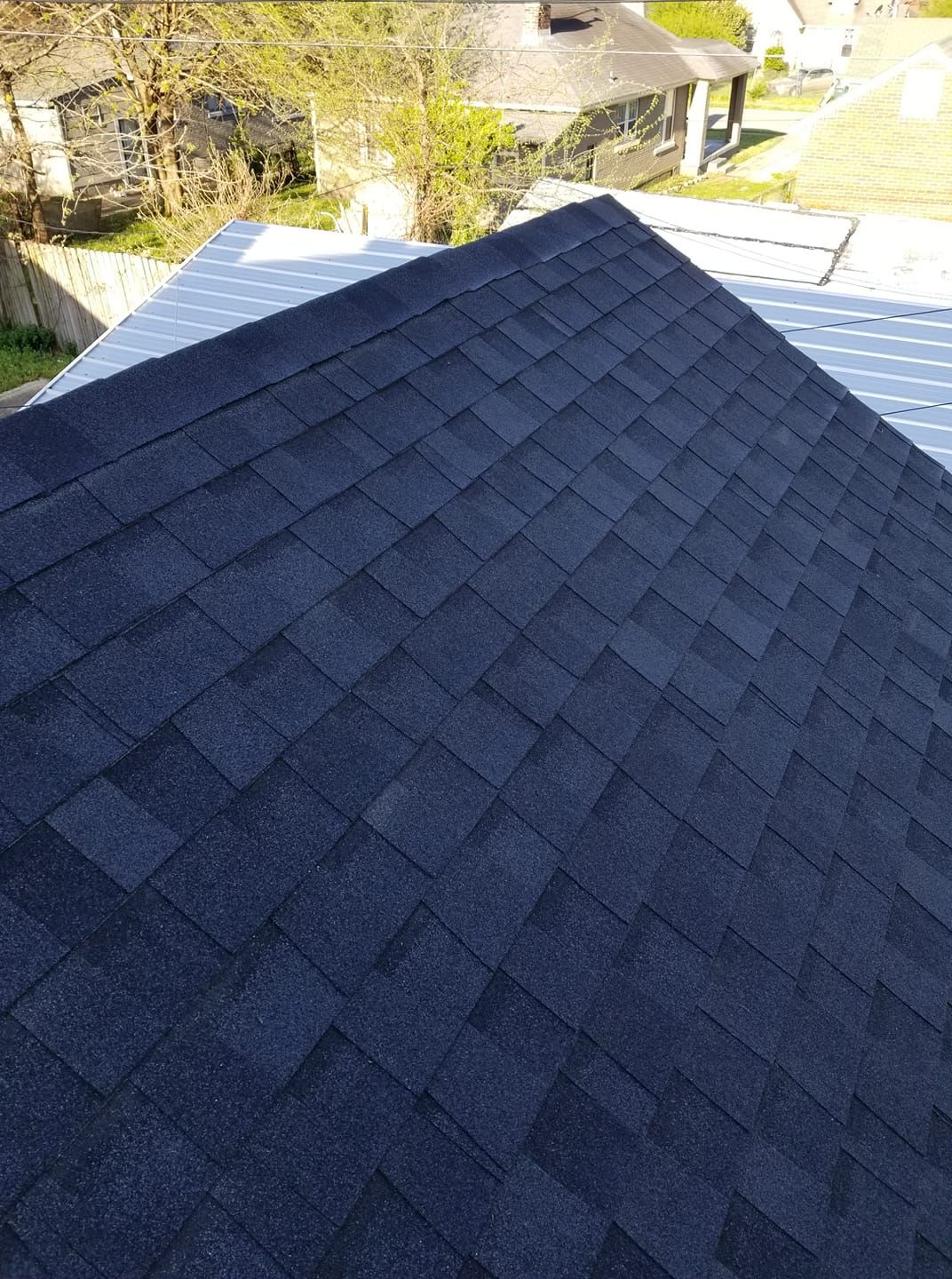 Dark asphalt shingle roof with visible angles, sunlight.