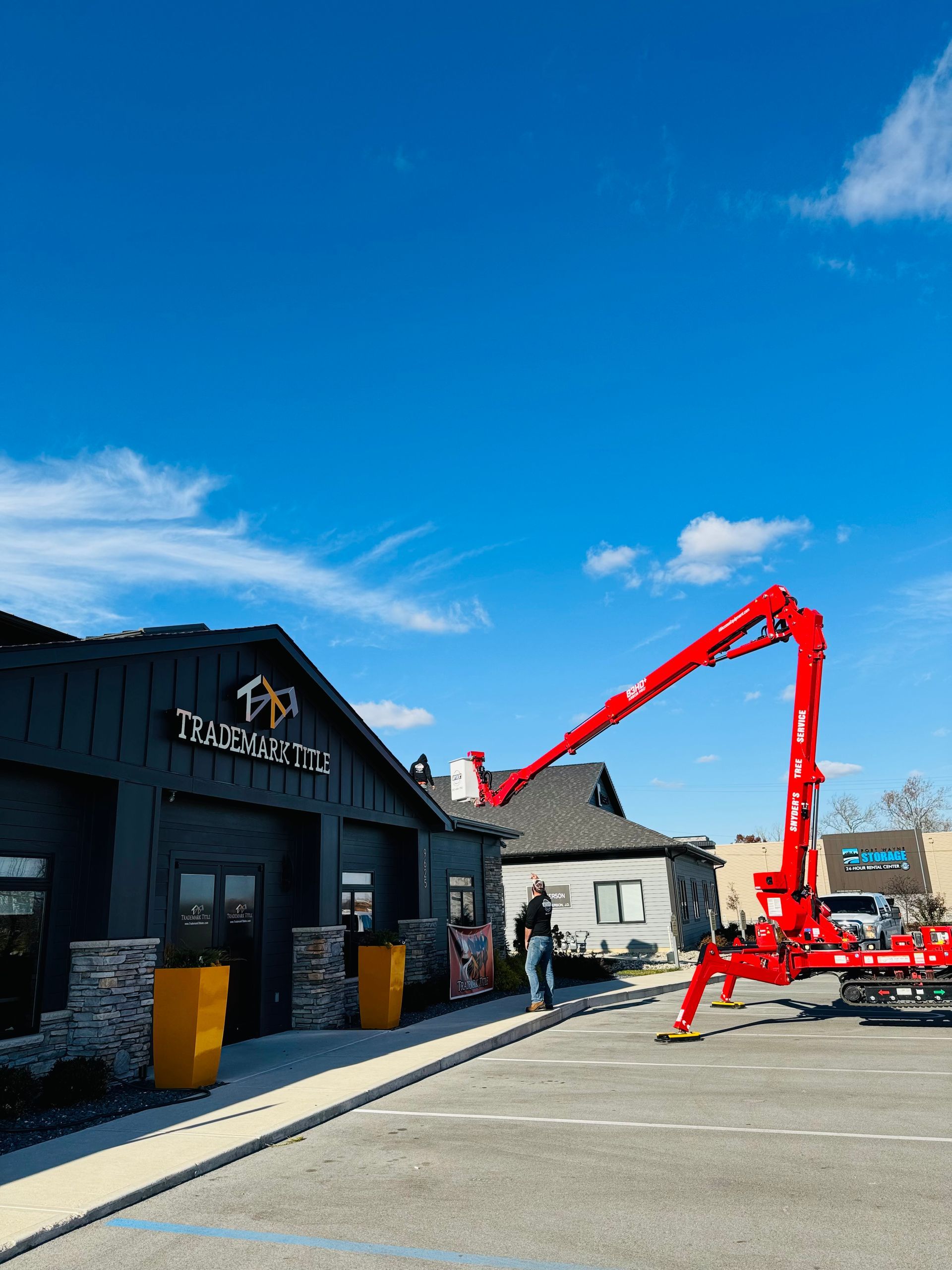 Red concrete pump truck pouring concrete on a building under a blue sky.