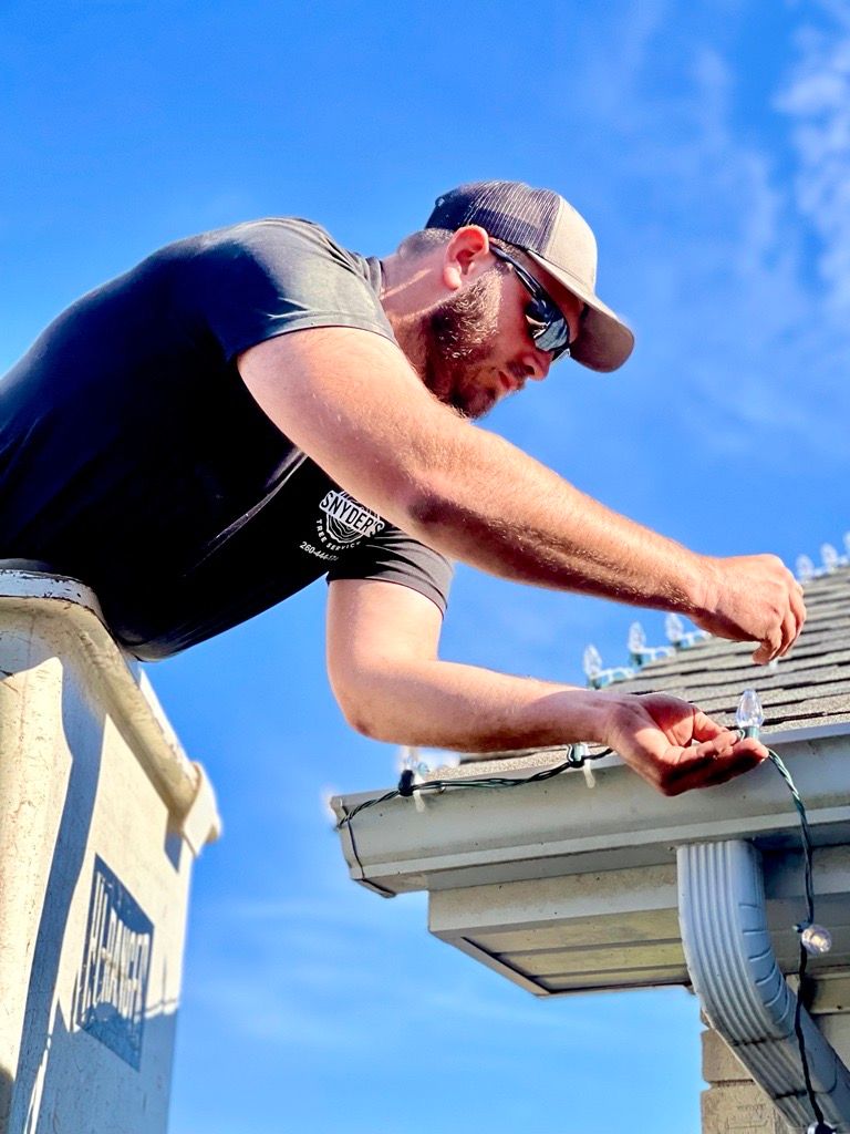 Man on a roof installing Christmas lights on a sunny day.