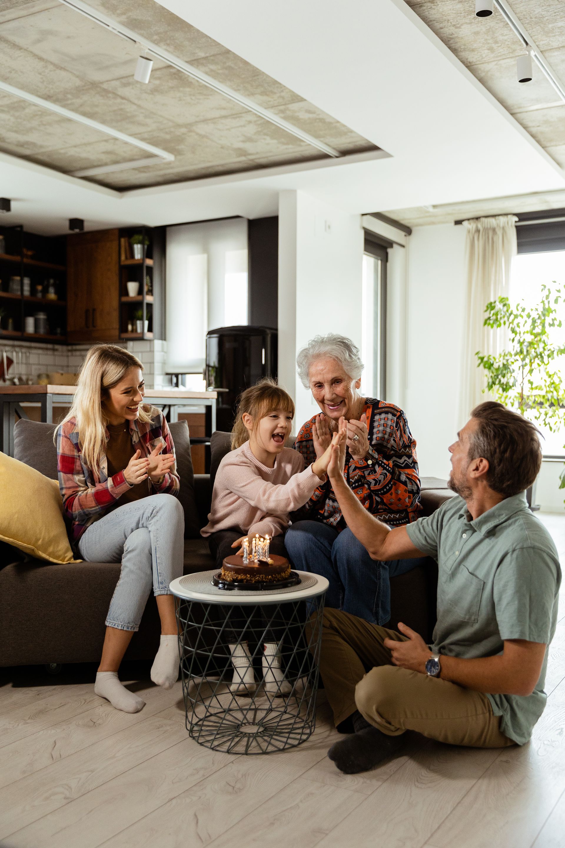 Friends chatting in a cozy living room around a small table with coffee and dessert
