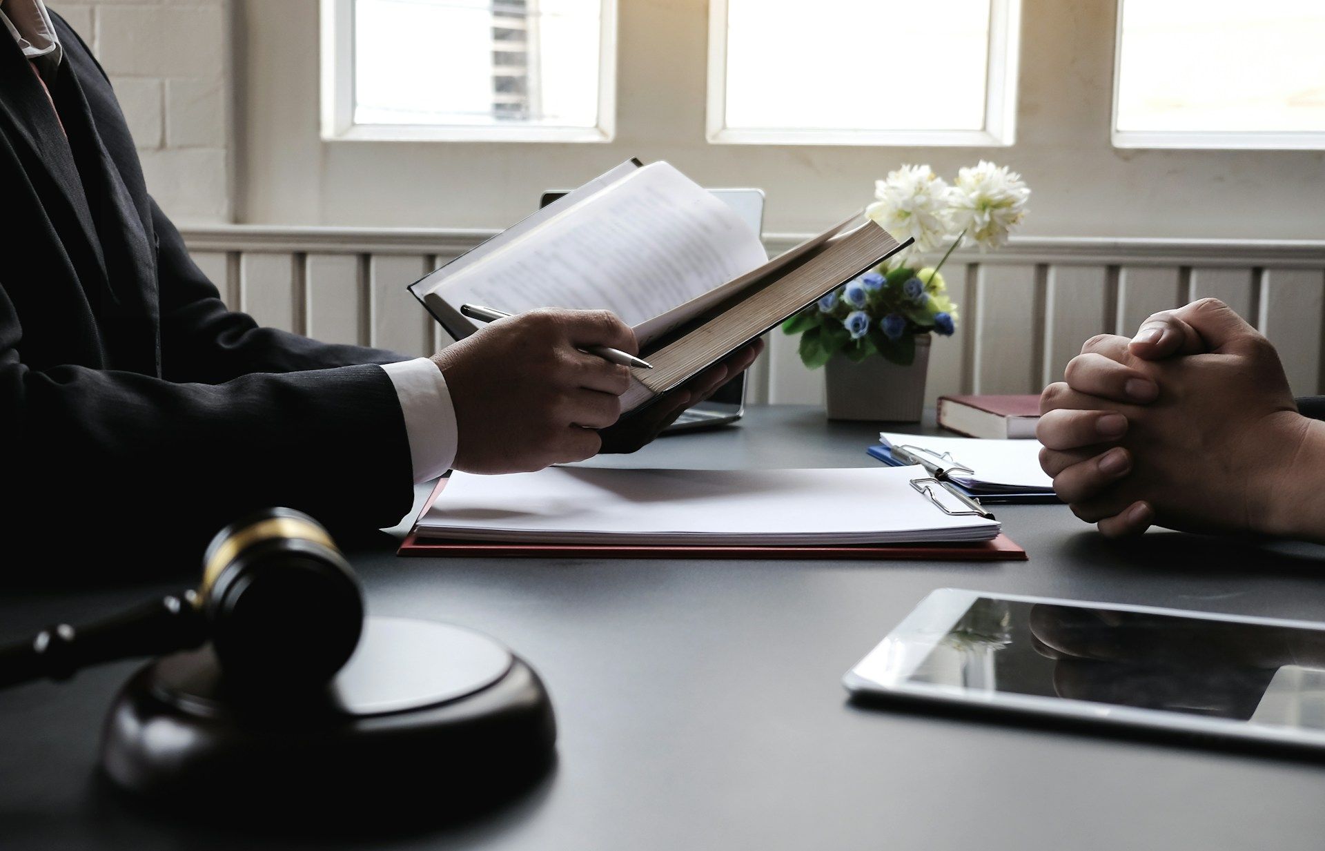 Lawyer meeting at a desk with paperwork, gavel, and tablet in a bright office