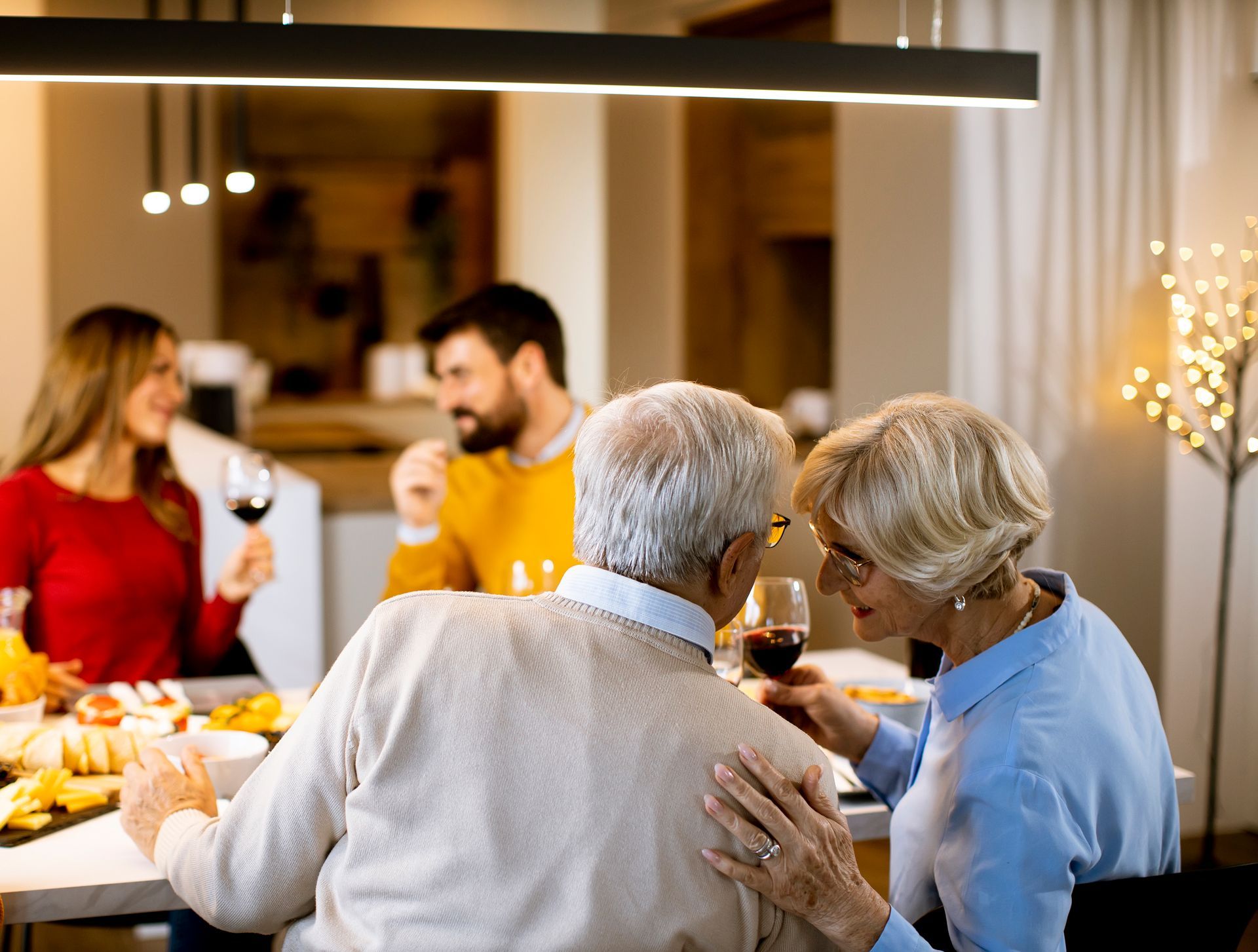 Friends sharing drinks around a dining table at a warmly lit dinner party