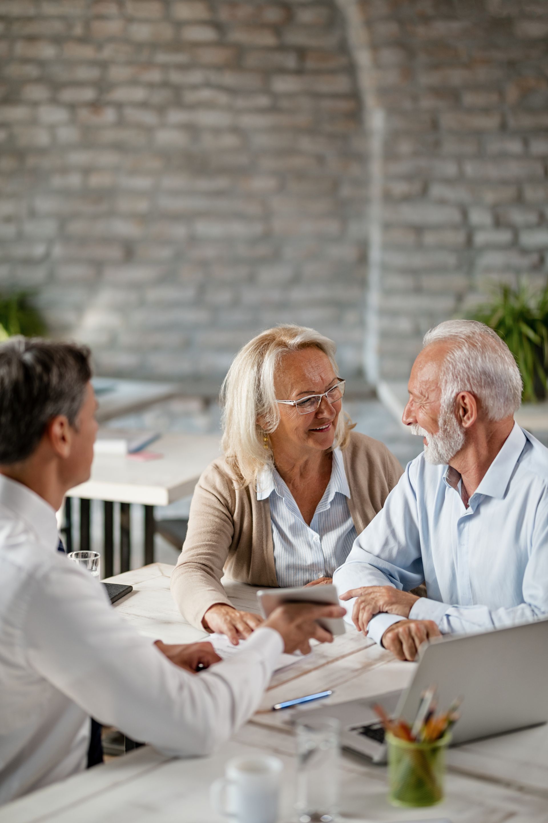 Three people discussing documents at a table in a bright office space