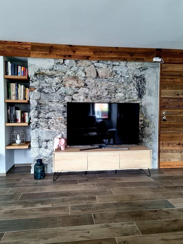 Télévision devant mur en pierres sèches et boiseries