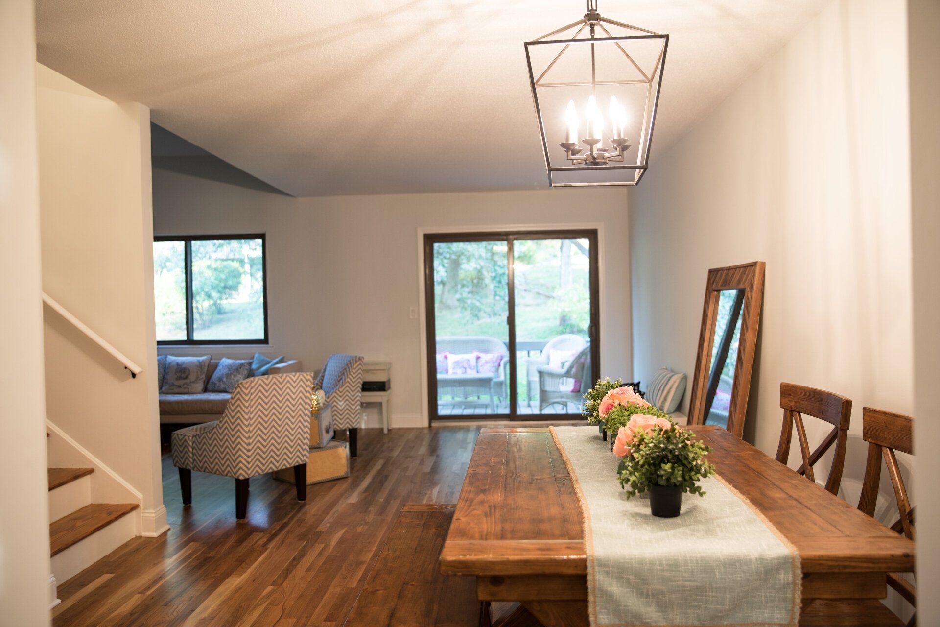 A dining room with a wooden table, cherry hardwood flooring, chairs and a sliding glass door.