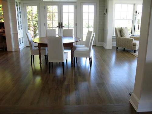 Dining room with round table, white chairs, wood floor, and natural light.