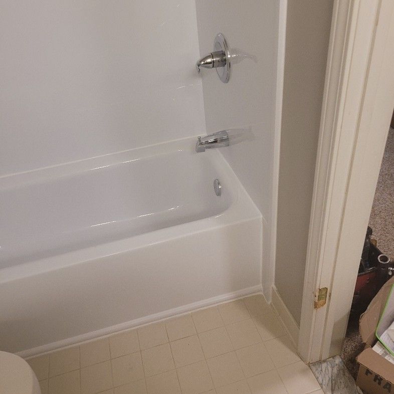 White bathtub with chrome fixtures, in a corner of a bathroom with a partially visible doorway.