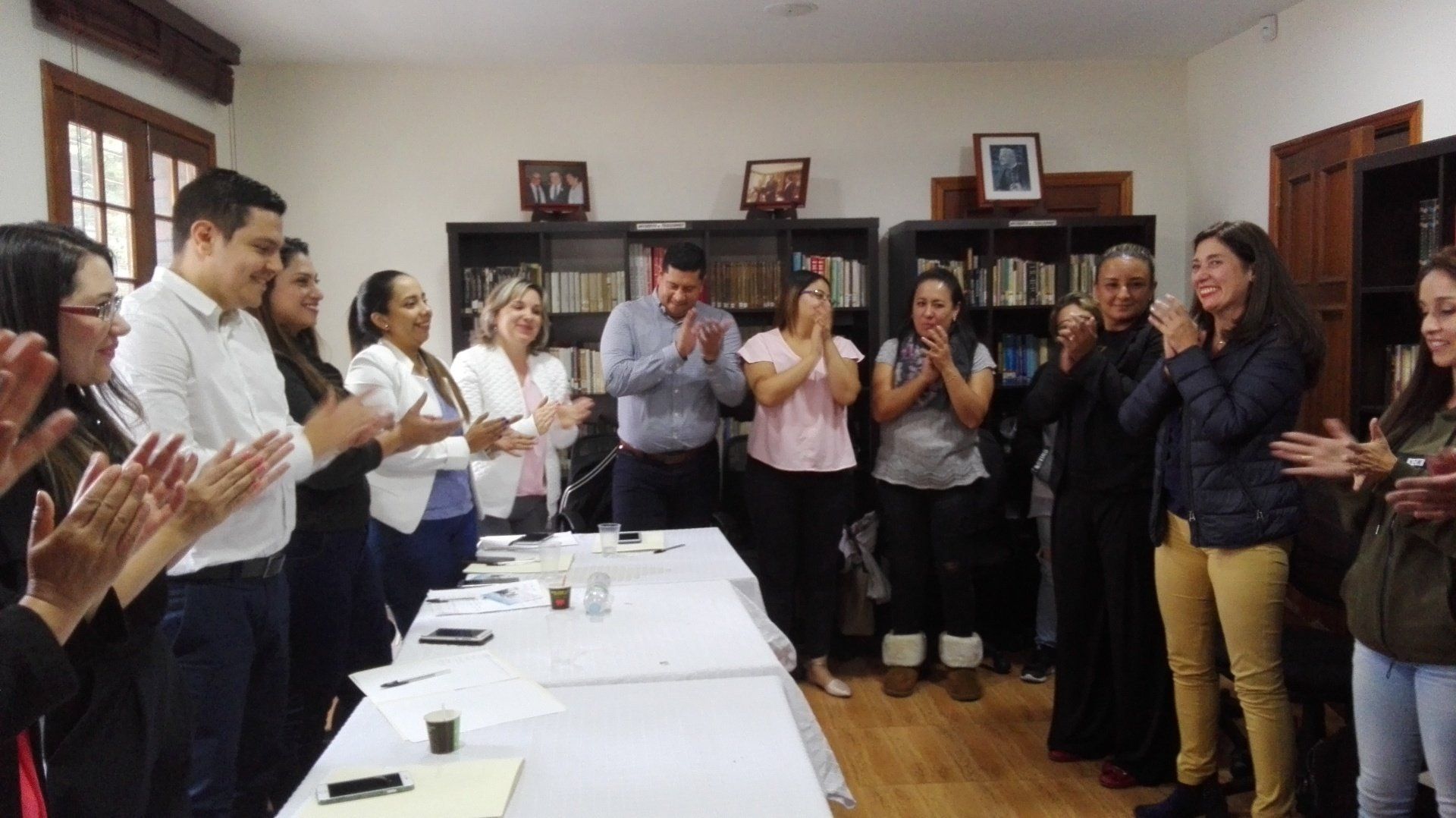 Grupo de personas sosteniendo certificados, sonriendo en una habitación bien iluminada.