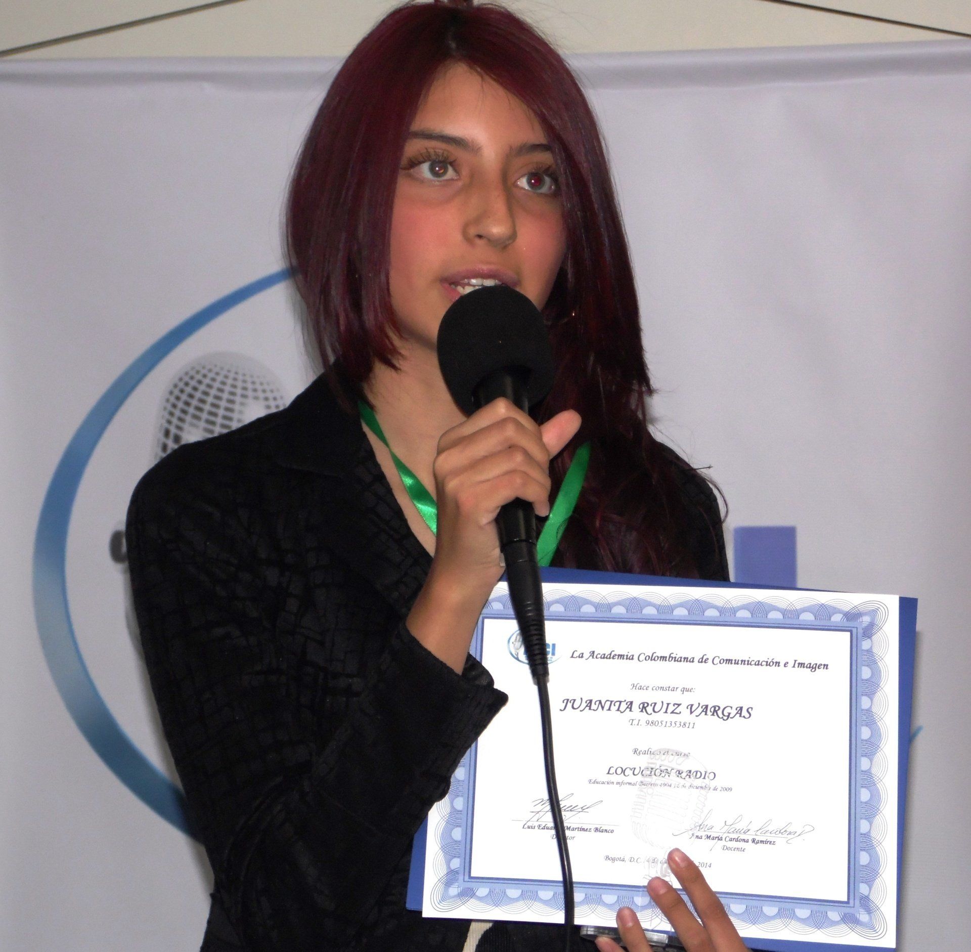 Mujer con chaqueta vaquera hablando por un micrófono en un estudio de grabación.