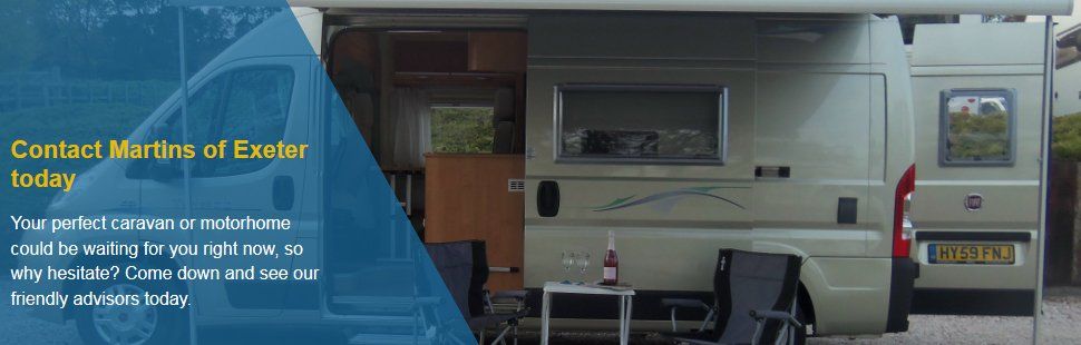 Caravan with awning and a table and chairs outside it with a bottle of wine of the table