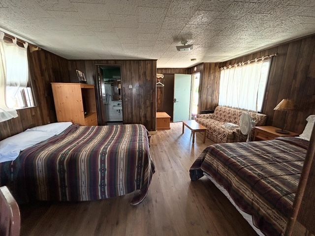 Cozy cabin room with two beds, a sofa, and wooden paneling.
