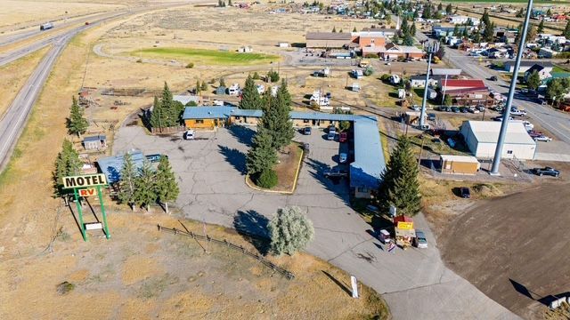 Aerial view of a motel with a long, blue roof. A highway runs alongside it.