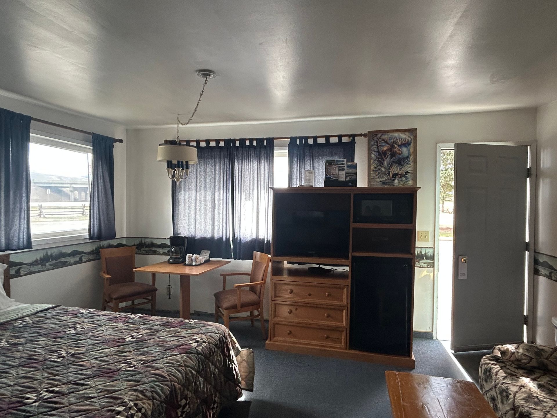 A hotel room with two beds , a table , chairs and a television.